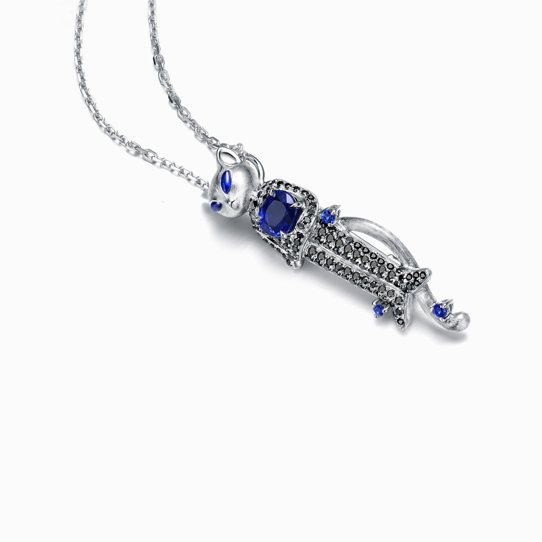 TASA 18K white gold sculptural cat pendant side view, blue sapphire centre stone with black diamond pavé body and brushed gold head, white background