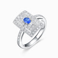 TASA 18K white gold Art Deco ring with 0.14ct oval blue sapphire in rectangular double diamond halo, side view on white background