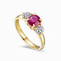 TASA 18K yellow gold three-stone ring featuring 1.15ct natural oval ruby flanked by two 0.50ct round brilliant diamonds, side view on white background